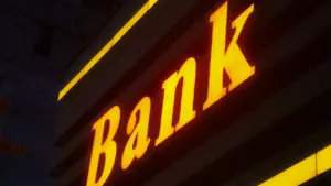 Šviečianti banko iškaba tamsiame fone, simbolizuojanti finansines operacijas ir saugumą.