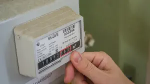 Žmogus tikrina elektros skaitiklio rodmenis, ruošdamasis sužinoti rugpjūčio 11 dienos elektros kainas.