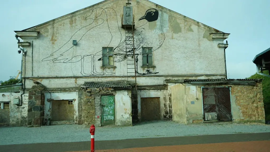 Senas pastatas su graffiti piešiniu ir gaisrininko hidrantu miesto aplinkoje.