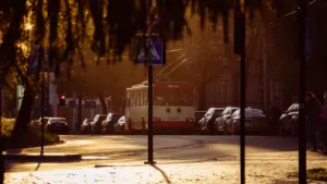 Viešasis transportas Vilniaus gatvėje šiltuoju metų laiku, simbolizuojantis judumą mieste.